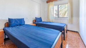 A room with two beds, a window with curtains, and a wooden ceiling beam. - 131-POMPEYO II. Apartment located in Cambrils only 300m from the beach (Cambrils)