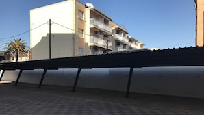 Un immeuble doté de nombreux balcons, d’un rez-de-chaussée carrelé et surplombant un ciel dégagé.