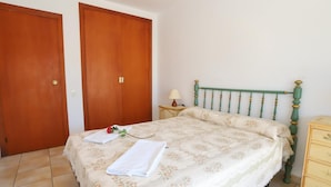 Une chambre à coucher comprenant un lit, une table de chevet, une commode et deux portes en bois.