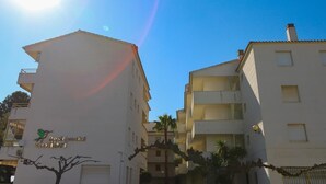 A residential building with a flat roof, multiple balconies, and a clear sky.