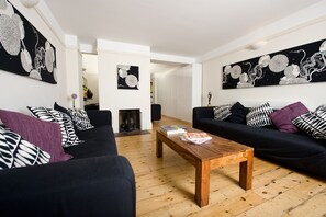 A modern living room with black sofas, a wooden coffee table, and abstract wall art.