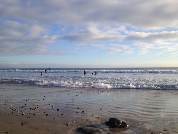 A beach with waves, rocks, and people in the water.