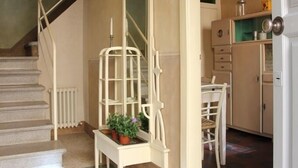 Una escala condueix a un rell de repos amb una banca blanca i plantes en testos. Es veu una cuina a través d'una obertura.