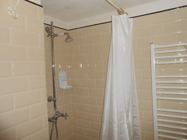 A shower with a white curtain, a white towel rack, and beige tiled walls. - Typical style house in one of the historic streets in the center of Lucca (lucca)