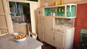 Cuina amb taula de menjador, armaris i finestra amb vista a vegetació.