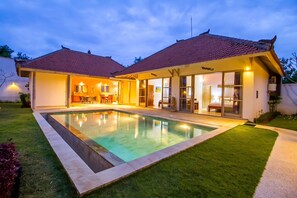 Ein zweistöckiges Haus mit Pool, großen Fenstern und einem gepflegten Rasen.