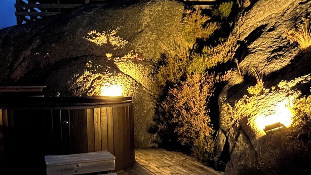 Eine Holzterrasse mit Whirlpool und Treppe zu einem Holzbau.