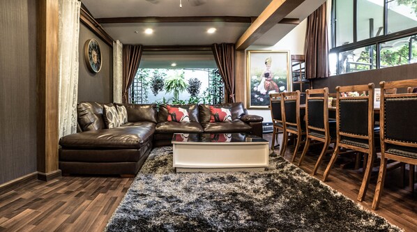 A modern living room with a sectional sofa, a coffee table, and a dining area with wooden chairs.