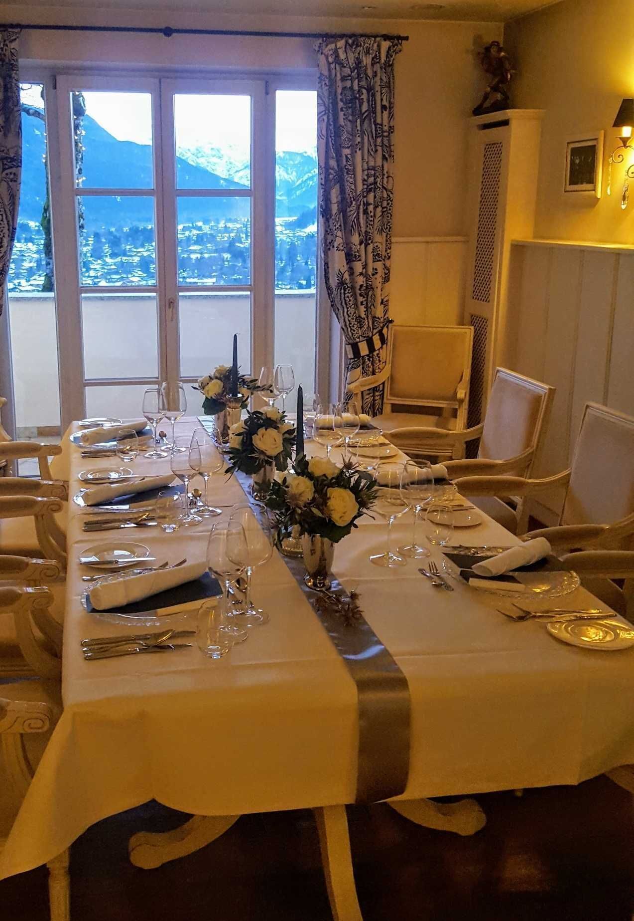 A dining table set for a meal with a view of mountains through large windows.
