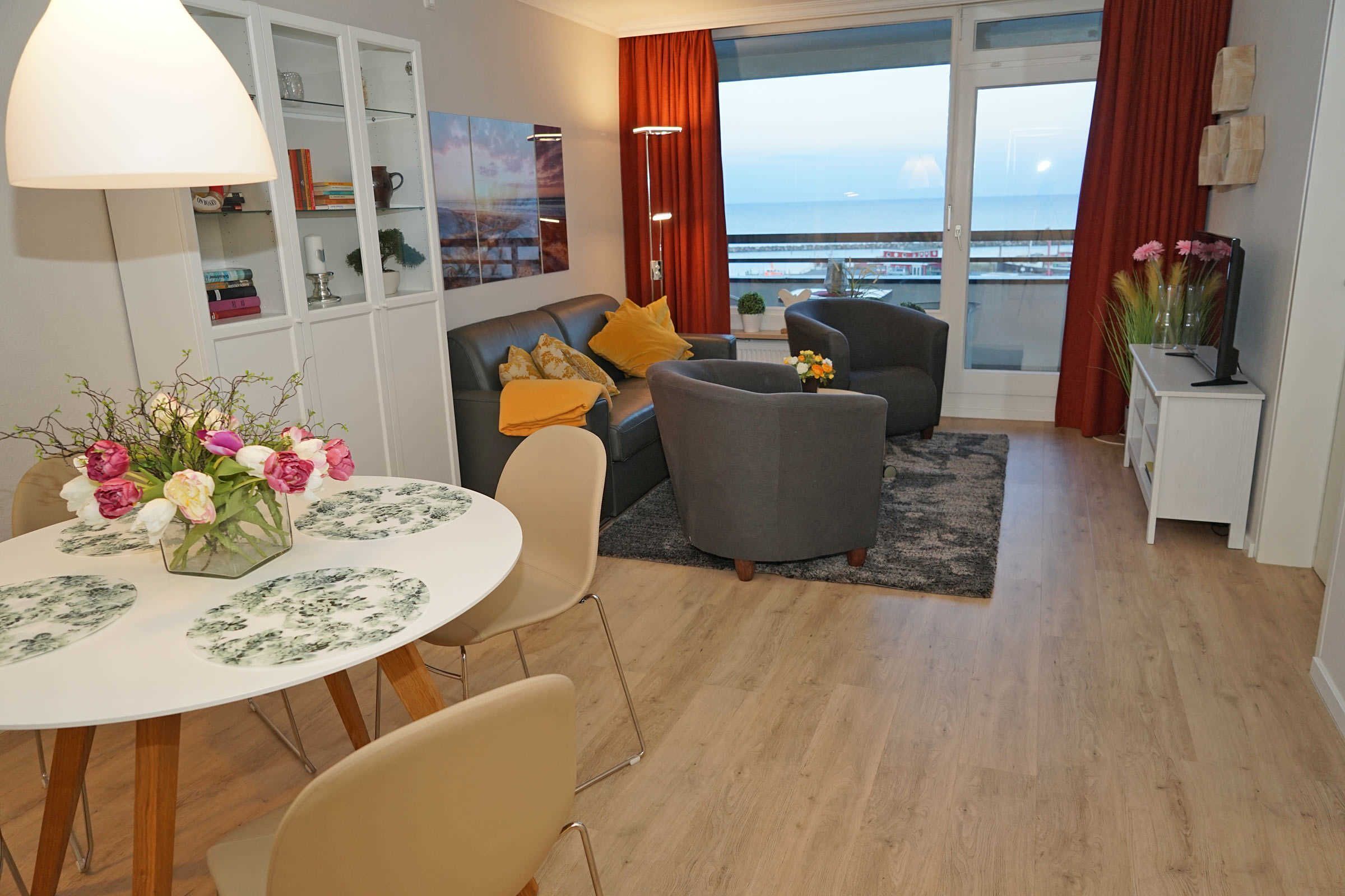 Een moderne woonkamer met een eethoek, een bank en uitzicht op zee.