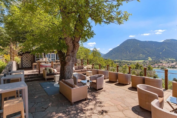 An outdoor seating area with wicker furniture and a view of a lake and mountains.