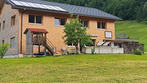 Un bâtiment à deux étages, doté d’un toit en pente, de panneaux solaires et d’une structure de jeu en bois.
