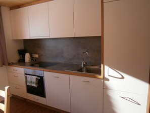 Eine kompakte Küche mit Backofen, einer Kaffeemaschine und einem Spülbecken.