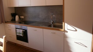 A compact kitchen with a built-in oven, a coffee maker, and a sink.