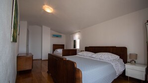 A bedroom with a double bed, a nightstand, a dresser, and a window with curtains. - Charming stone house with panoramic sea and mountain view (Lokva Rogoznica)