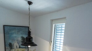 A staircase with a stone wall, a hanging light fixture, a window with blinds, and a small table with a vase and a bag. - Charming stone house with panoramic sea and mountain view (Lokva Rogoznica)