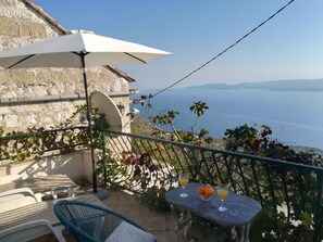 Un balcon avec une table, des chaises et un parasol, offrant une vue panoramique.