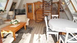 Ein gemütliches Loft mit einem Holztreppenhaus, einem Esstisch und einem Fernseher.