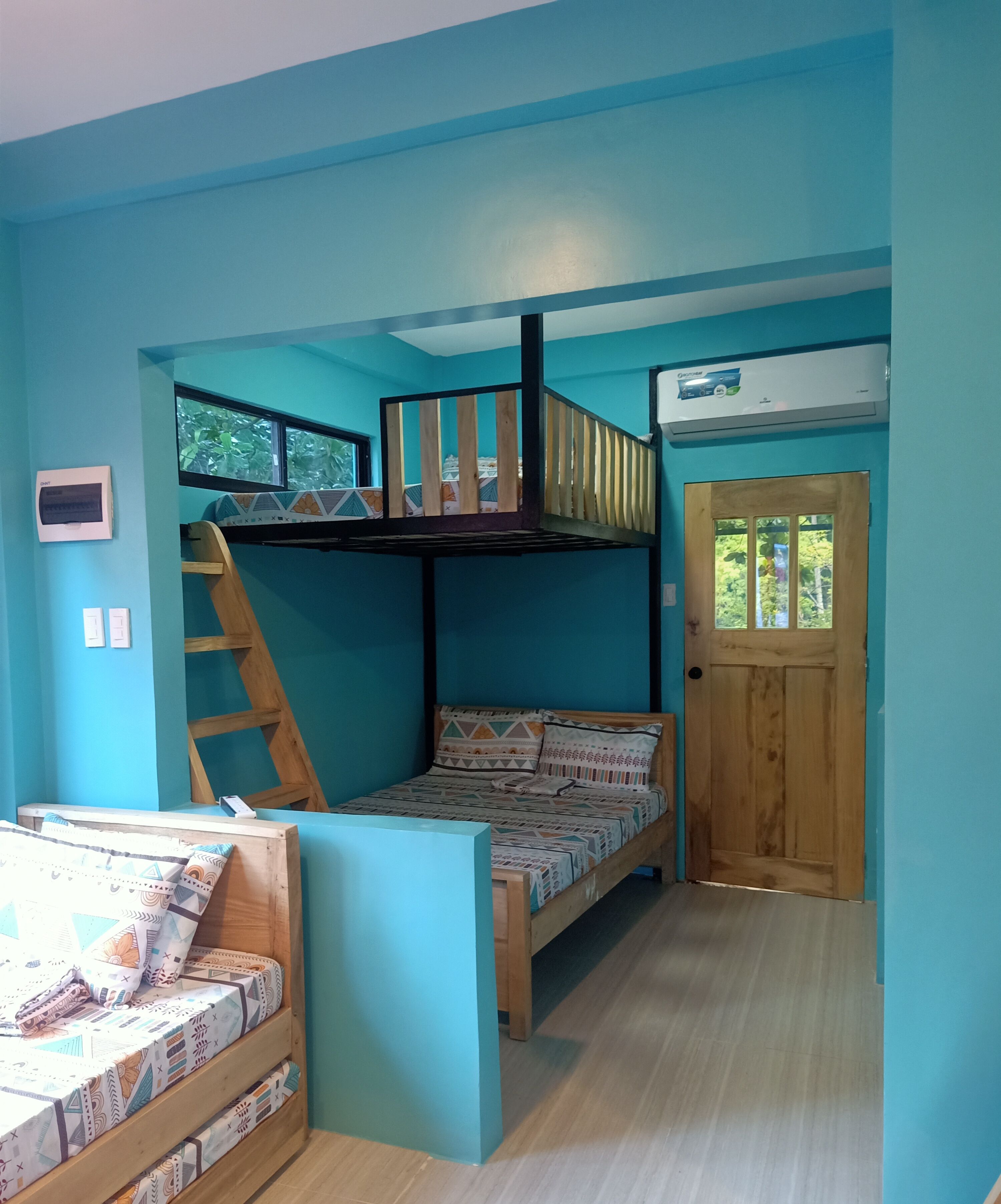A bunk bed room with a wooden ladder, a window, and a door.