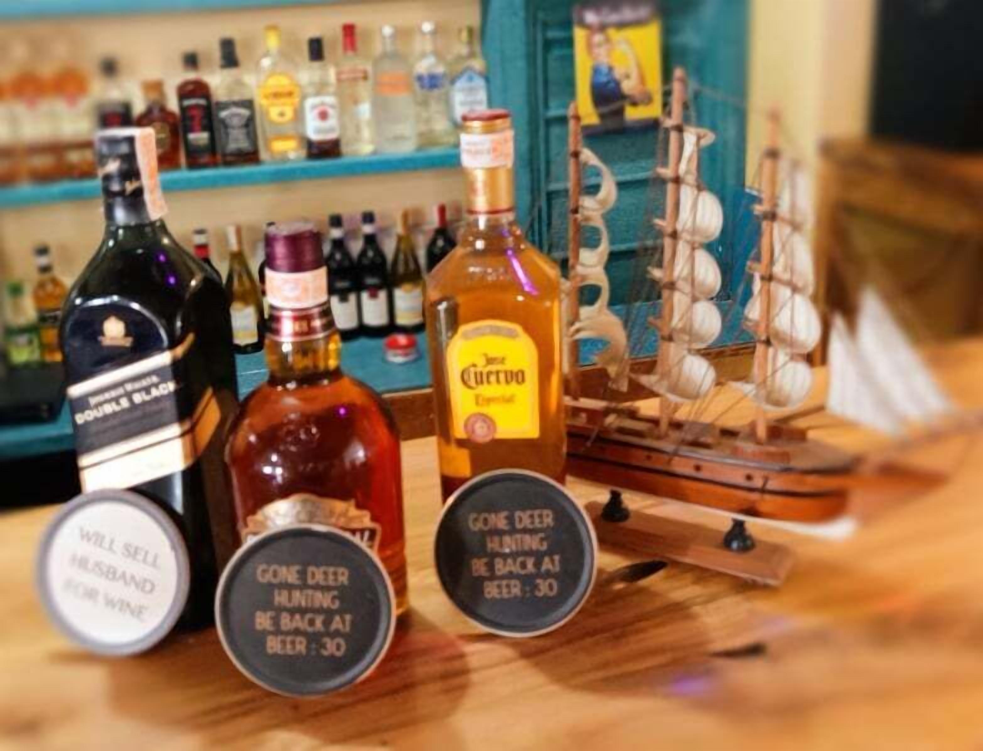 A bar counter with various bottles of alcohol, including a bottle labeled "Gone Deer Hunting Be Back at Beer: 30".