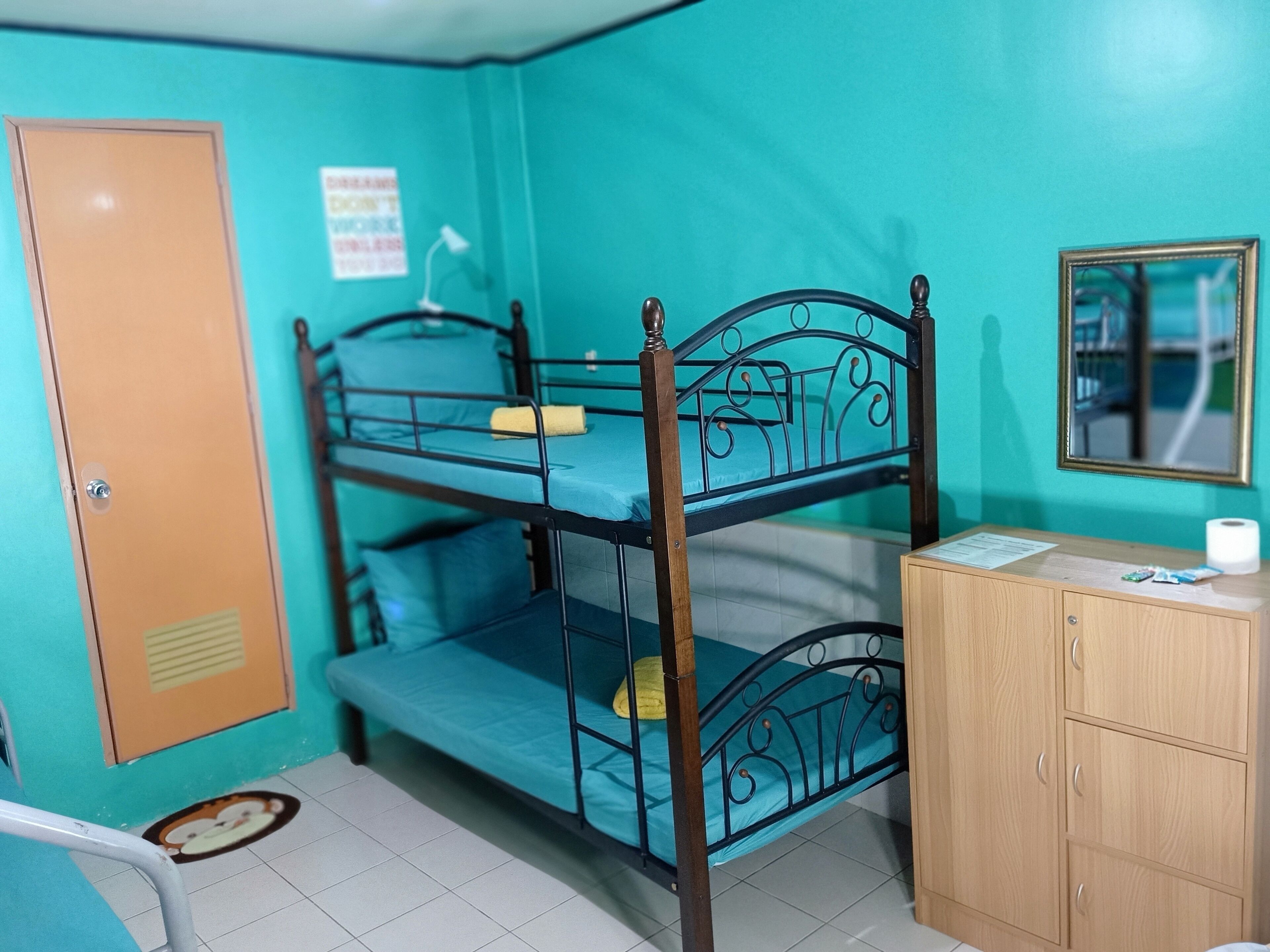 Une chambre avec un lit superposé, une armoire en bois, un bureau et un miroir.