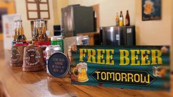 A bar area with a 'Free Beer Tomorrow' sign, various beer bottles, and a refrigerator.