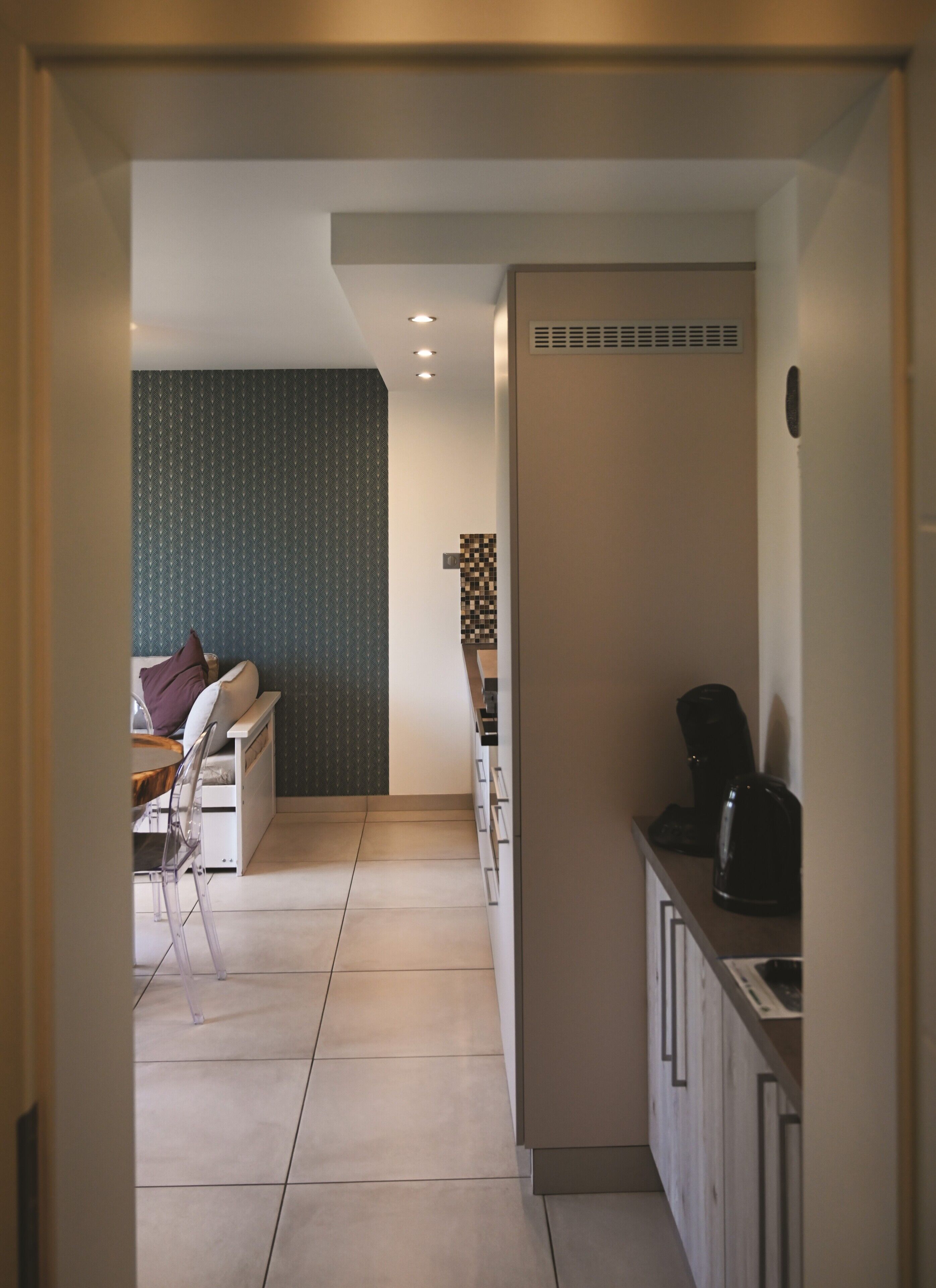 A modern kitchen with a built-in oven, a coffee machine, and a dining area with a table and chairs.