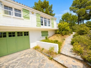 A two-story building with a stone pathway leading to a green door.