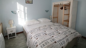 Une chambre à coucher avec un lit, des tables de chevet, une armoire et une fenêtre.