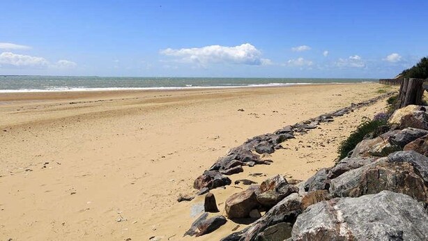 A beach with a rocky shoreline and a clear blue sky.