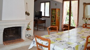 A dining room with a fireplace, a television, and a dining table.