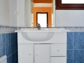 A bathroom with a white sink, a mirror, and a door leading to another room.