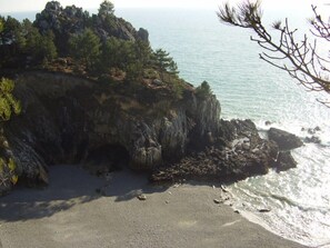 Une côte rocheuse avec une plage de sable et une vue sur la mer.
