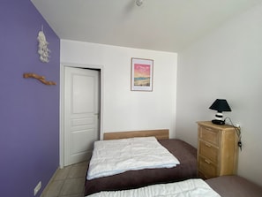 A bedroom with a bed, a wooden cabinet, a door, and a poster on the wall. - House near beach and shops in La Tranche-sur-Mer (La Tranche-sur-Mer)
