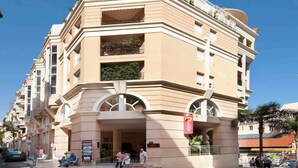 Un hôtel à plusieurs étages, doté d’une façade beige, de balcons et d’une entrée imposante.