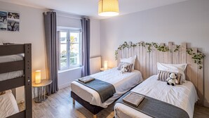Een slaapkamer met twee bedden, een raam, een lamp en een houten hoofdbord met begroeiing.