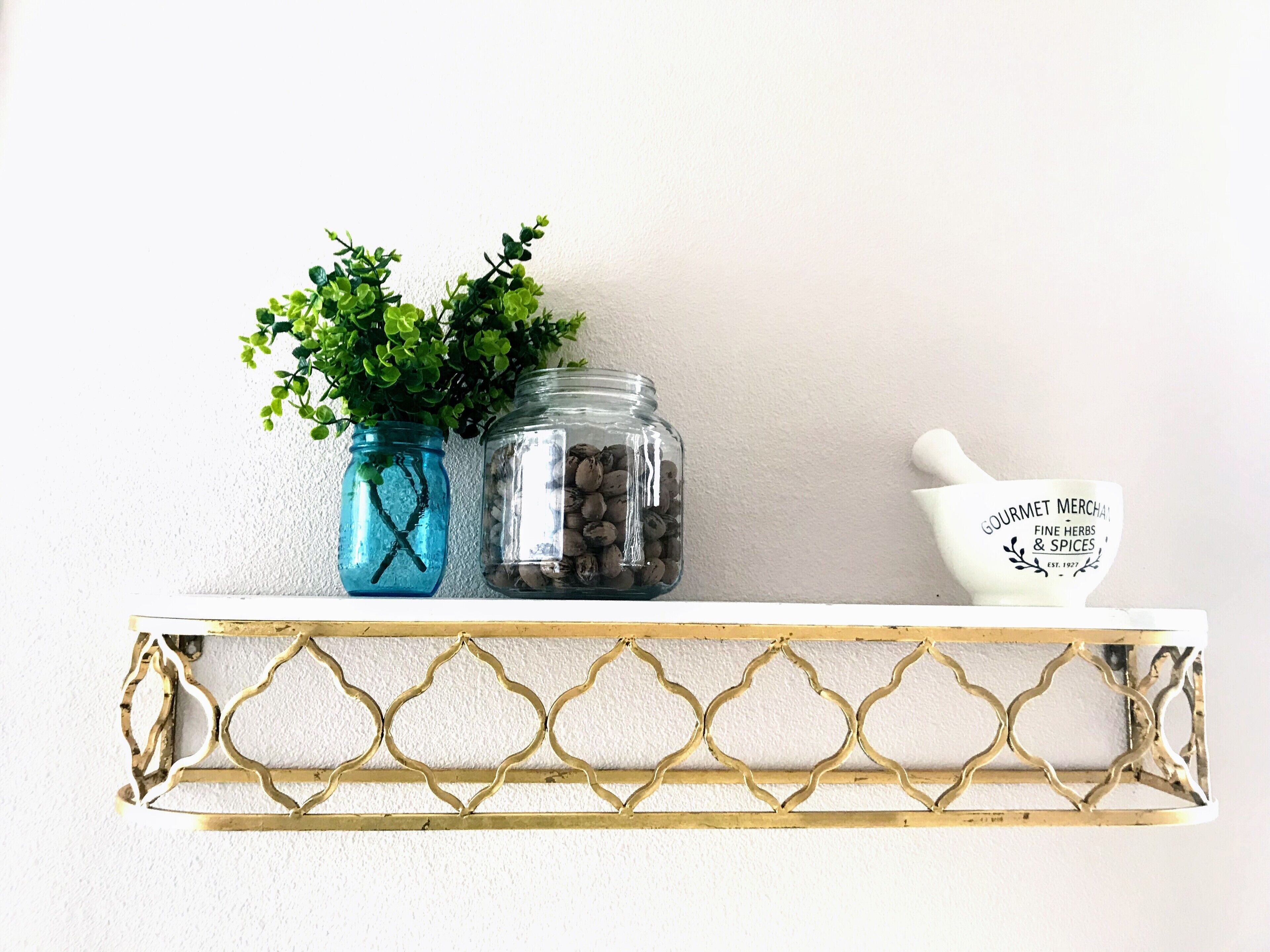 A shelf with two glass jars, one with green plants and the other with nuts, and a white ceramic bowl with text.
