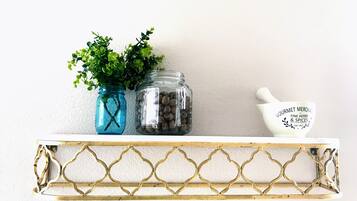 A shelf with two glass jars, one with green plants and the other with nuts, and a white ceramic bowl with text.
