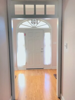A hallway with a white door, wooden flooring, and a decorative ceiling.