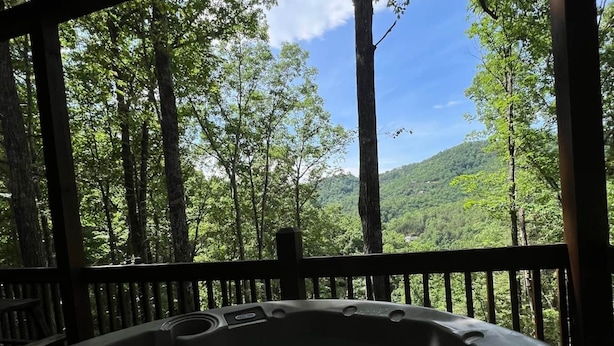 Ein Whirlpool, umgeben von einer Holzterrasse mit Blick auf einen Wald.