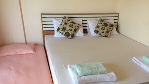 Un lit avec une tête de lit en bois, deux oreillers, une serviette pliée et une couverture.