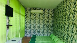 Une chambre avec un lit, un téléviseur fixé au mur et un papier peint à motifs.