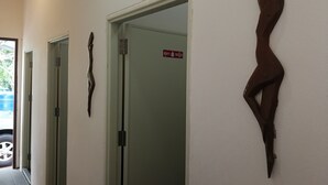 Un couloir avec trois portes, dont l’une est signalée par un panneau indiquant les toilettes.