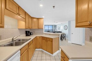 A modern kitchen with wooden cabinets, a built-in dishwasher, and a large window offering a view.
