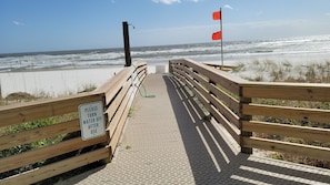 A wooden boardwalk leading to the beach with a sign instructing to turn off the water after use.