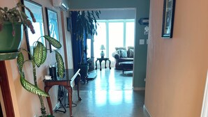 A spacious hallway with a marble floor, a green potted plant, a fan, and a sofa in the background.