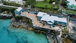 A coastal property with a large house, a dock, and clear turquoise waters.