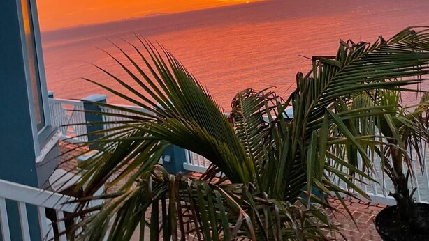A balcony with a view of the ocean during sunset.