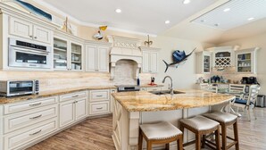 A spacious kitchen with white cabinetry, a large island with stools, and a built-in oven. - WOW (Wade on the Water) - Amazing Beachfront with all the extras! (Crystal Beach)