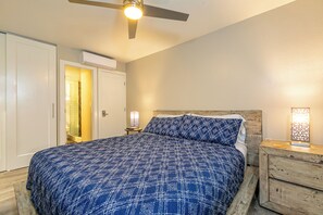 Ein Schlafzimmer mit einem Bett, einem Deckenventilator, einem Nachttisch und einer Wandleuchte.
